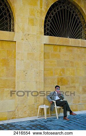 A man sits on a chair beside a yellow wall smoking a cigarette; Beirut, Lebanon View Large Photo Image Picture - A man sits on a chair beside a yellow wall smoking a cigarette; Beirut, Lebanon. Fotosearch