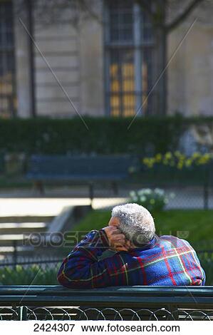 Stock Photo - A man sits relaxing on a park bench in Marais district; Paris, France. Fotosearch