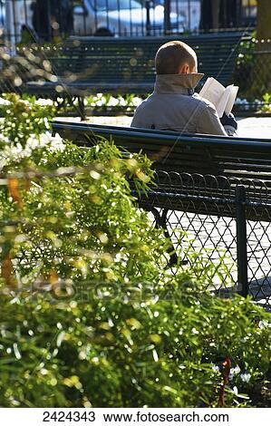 A man sitting on a bench reading a book, Canal Saint Martin; Paris, France View Large Photo Image Stock Image - A man sitting on a bench reading a book, Canal Saint Martin; Paris, France. Fotosearch