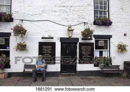 Stock Image - A Man Sitting Outside A Restaurant; Warkworth, Northumberland, England. Fotosearch