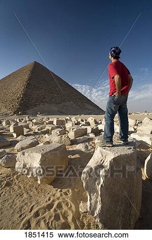 Stock Photography - A Man Standing Near A Pyramid In The Desert. Fotosearch