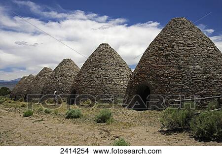 Picture - A man stands in front of door looking at top of the Ward Charcoal Ovens, Historical preservation; Ely, Nevada, United States of America. Fotosearch