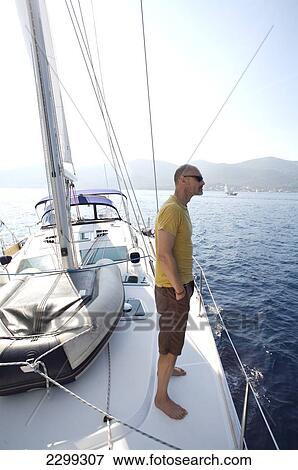 A man stands on the deck of a sailboat; Croatia View Large Photo Image Stock Photo - A man stands on the deck of a sailboat; Croatia. Fotosearch