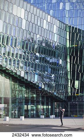 Picture - A man taking a photograph of Harpa Concert Hall and Conference Centre; Reykjavik, Iceland. Fotosearch