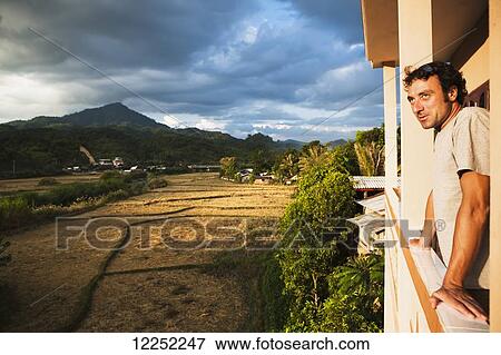 Stock Photo - A man views a remote Northern Laos village; Vieng Thong, Laos. Fotosearch