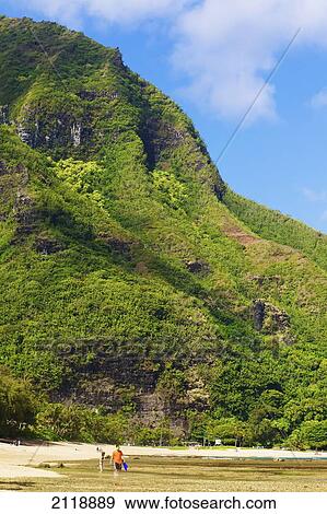 Stock Photo - A man walks in the shallow water at Tunnel's Beach; Haena, Kauai, Hawaii, United States of America. Fotosearch