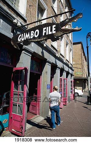 A Man Walks Past A Crocodile Shaped Sign For Gumbofile, A Cafe Bar, In The French Quarter, New Orleans, Louisiana, Usa View Large Photo Image Stock Photo - A Man Walks Past A Crocodile Shaped Sign For Gumbofile, A Cafe Bar, In The French Quarter, New Orleans, Louisiana, Usa. Fotosearch