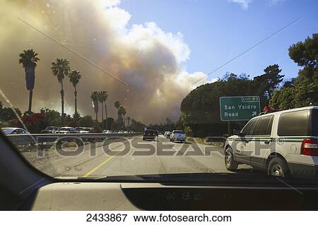 Stock Photo - A massive cloud of smoke darkens the sky above Santa Barbara as a US Forest Service firefighting vehicle drives west on US 101 through Montecito on the second day of the Jesusita Fire; Santa Barbara, California, United States of America. Fotosearch