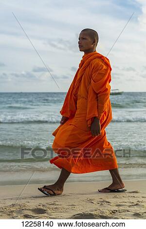 Stock Image - A monk walks on the sand of Serendipity Beach; Sihanoukville, Cambodia. Fotosearch