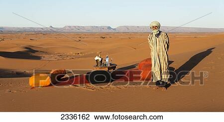 A Moroccan Man Stands Beside A Blanket And Cushions Set Up For A Meal In The Desert; Morocco View Large Photo Image Stock Image - A Moroccan Man Stands Beside A Blanket And Cushions Set Up For A Meal In The Desert; Morocco. Fotosearch