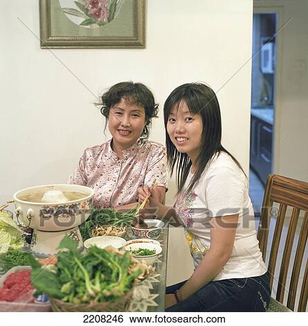 Stock Photograph - A Mother And Daughter Share A Traditionnal Chinese Hot Pot Meal With Meat, Leafy Vegetables, And Mushrooms. Beijing, China.. Fotosearch