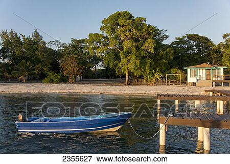 A Motorboat Tied To A Wooden Dock Off The Shore Of An Island; Bay Islands, Honduras View Large Photo Image Stock Photo - A Motorboat Tied To A Wooden Dock Off The Shore Of An Island; Bay Islands, Honduras. Fotosearch