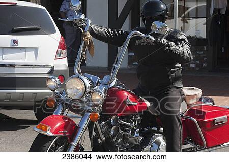 Picture - A motorcyclist dressed in black on a red motorcycle; California, United States of America. Fotosearch