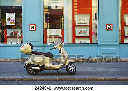 A motorized scooter parked outside a blue building along a street, Canal Saint Martin; Paris, France View Large Photo Image Stock Image - A motorized scooter parked outside a blue building along a street, Canal Saint Martin; Paris, France. Fotosearch