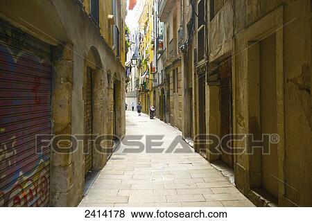 Stock Photo - A narrow street in between buildings; Barcelona, Spain. Fotosearch
