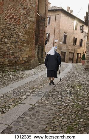 Stock Photography - A Nun Walking Up A Cobblestone Street; Italy. Fotosearch