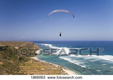 Stock Image - A Paraglider Soars Free Over The Cliffs Of The Bukit Peninsula In Bali; Bali, Indonesia. Fotosearch
