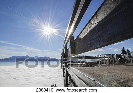 Stock Image - A patio above the clouds with a view of the swiss alps; Locarno, Ticino, Switzerland. Fotosearch