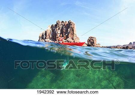 Stock Image - A Person Paddling On The Water With A View Of A Large Rock Underwater At Los Islotes National Marine Park On Espiritu Santos Island Near La Paz; Baja California Mexico. Fotosearch