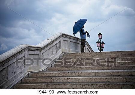 A Person Stands Holding An Umbrella Under A Cloudy Sky At The Top Of The Steps; Venice Venezia Italy View Large Photo Image Stock Image - A Person Stands Holding An Umbrella Under A Cloudy Sky At The Top Of The Steps; Venice Venezia Italy. Fotosearch