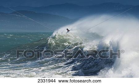 Picture - A Person Surfing In The Waves Along The Coast Of Cape Trafalgar; Cadiz, Andalusia, Spain. Fotosearch