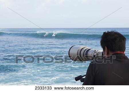 A photographer snaps pictures of far away surfers with his large telephoto lens; Oahu, Hawaii, United States of America View Large Photo Image Stock Image - A photographer snaps pictures of far away surfers with his large telephoto lens; Oahu, Hawaii, United States of America. Fotosearch