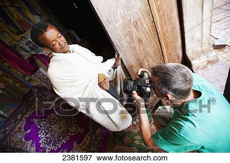 Stock Photo - A photographer taking a picture of a man wrapped in white cloth at a monastery on an island in Lake Tana, close to Bahir Dar; Ethiopia. Fotosearch