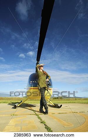 A pilot stands waiting with a helicopter on a landing pad; Kilauea, Hawaii, United States of America View Large Photo Image Stock Image - A pilot stands waiting with a helicopter on a landing pad; Kilauea, Hawaii, United States of America. Fotosearch