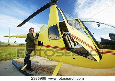 A pilot stands waiting with a helicopter on a landing pad; Kilauea, Hawaii, United States of America View Large Photo Image Stock Photograph - A pilot stands waiting with a helicopter on a landing pad; Kilauea, Hawaii, United States of America. Fotosearch