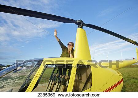Stock Photo - A pilot waves while waiting with a helicopter on a landing pad; Kilauea, Hawaii, United States of America. Fotosearch