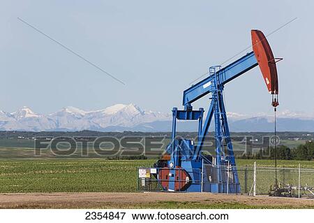 A Pumpjack In A Field With The Rocky Mountains In The Distance; Alberta, Canada View Large Photo Image Stock Photo - A Pumpjack In A Field With The Rocky Mountains In The Distance; Alberta, Canada. Fotosearch