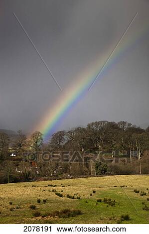 Stock Image - A Rainbow And Storm Clouds; Dumfries Scotland. Fotosearch