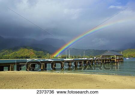 Stock Photograph - A rainbow over Hanalei pier in Hanalei bay; Kauai, Hawaii, United States of America. Fotosearch