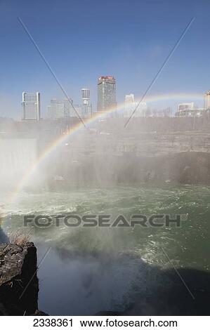Stock Image - A Rainbow Over Niagara Falls And Gorge With Mist And Blue Sky; Niagara Falls, New York, United States Of America. Fotosearch