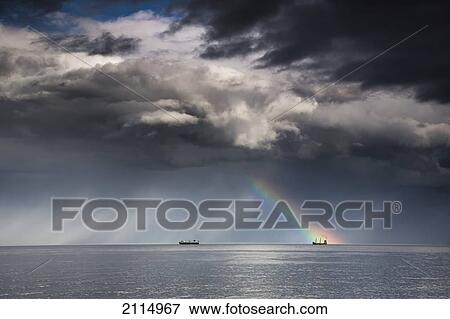 A Rainbow Through Storm Clouds Over An Ocean With Two Ships; Whitley Bay Northumberland England View Large Photo Image Stock Photo - A Rainbow Through Storm Clouds Over An Ocean With Two Ships; Whitley Bay Northumberland England. Fotosearch