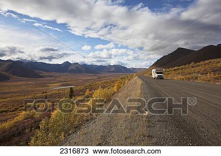 Stock Image - A Recreational Vehicle Drives On Dempster Highway Past Klondike Valley In Tombstone Territorial Park; Yukon Canada. Fotosearch