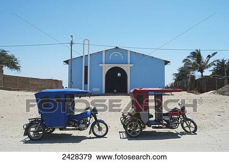 A red and blue three-wheeled cart sit on the sand outside a blue building with blue sky and palm trees; Sechura Desert, Peru View Large Photo Image Stock Photo - A red and blue three-wheeled cart sit on the sand outside a blue building with blue sky and palm trees; Sechura Desert, Peru. Fotosearch