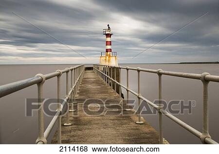 Stock Photo - A Red And White Striped Lighthouse At The End Of A Pier; Amble Northumberland England. Fotosearch