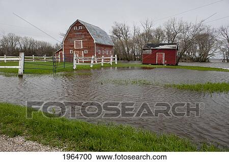 Stock Image - A Red Barn And Shed Surrounded By Water After Flooding; St. Francois Xavier Manitoba Canada. Fotosearch