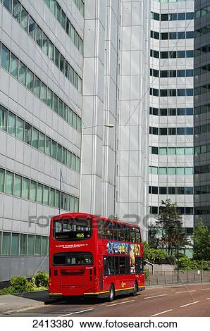Stock Image - A red double decker bus on the street below an office building, Croydon; London, England. Fotosearch