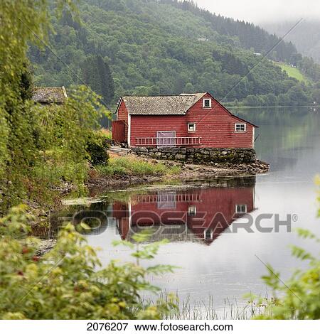 Stock Photo - A Red House Along The Water's Edge; Granvin Hordaland Norway. Fotosearch