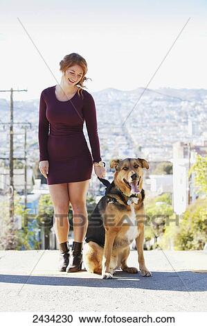 Stock Image - A redheaded girl is walking her dog; San Francisco, California, USA. Fotosearch