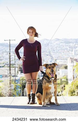 Stock Image - A redheaded girl is walking her dog; San Francisco, California, USA. Fotosearch
