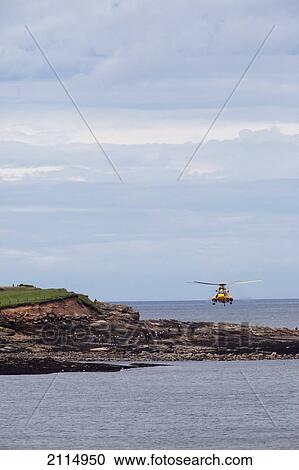 Stock Image - A Rescue Helicopter In Flight By The Coast; Northumberland England. Fotosearch