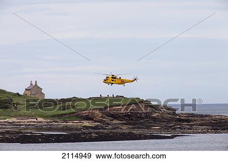 Stock Photo - A Rescue Helicopter Taking Off From Land On The Water's Edge; Northumberland England. Fotosearch