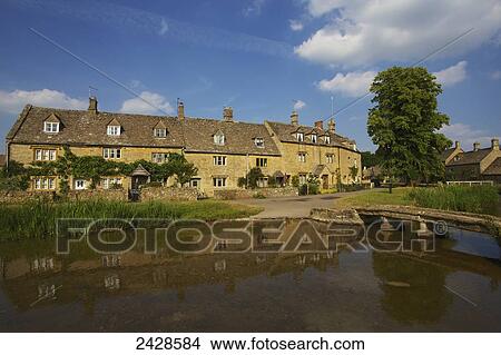 Picture - A residential building and it's reflection in water, Lower Slaughter Village, The Cotswolds; Gloucestershire, England. Fotosearch