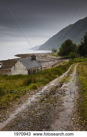 Stock Image - A Road And Weathered House At The Water's Edge; Ardnamurchan Argyl Scotland. Fotosearch