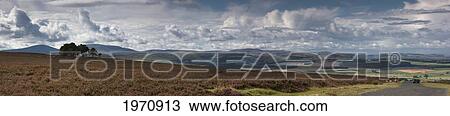 Stock Image - A Road Leading Into The Distance And Dramatic Clouds Over A Landscape; Northumberland England. Fotosearch