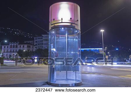 Stock Photo - A Round Telephone Booth Illuminated At Nighttime; Locarno, Ticino, Switzerland. Fotosearch