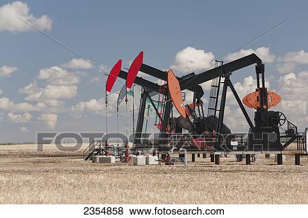 A Row Of Pump Jacks In A Field With Clouds And Blue Sky; Acme, Alberta, Canada View Large Photo Image Stock Photo - A Row Of Pump Jacks In A Field With Clouds And Blue Sky; Acme, Alberta, Canada. Fotosearch